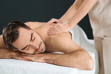 Fototapeta na wymiar Handsome man receiving back massage on black background. Spa service
