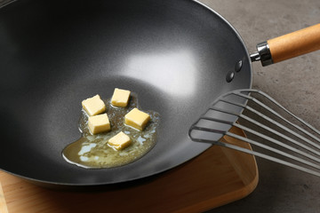 Frying pan with melting butter on grey table, closeup