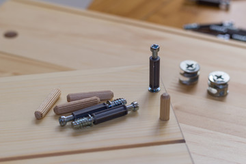 Screw being screwed into wood, dowels and furnishing accessories close-up with copy space