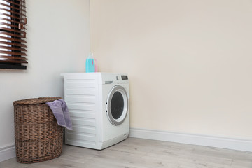 Modern washing machine and laundry basket indoors. Space for design