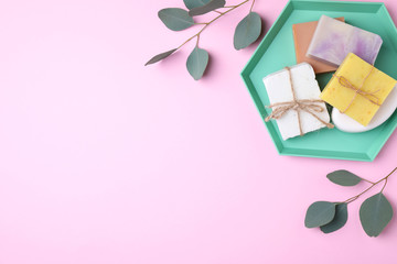 Flat lay composition with soap bars and green branches on color background. Space for text