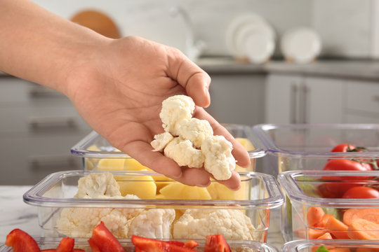 Woman Putting Cut Cauliflower Into Box And Containers With Raw Vegetables In Kitchen, Closeup