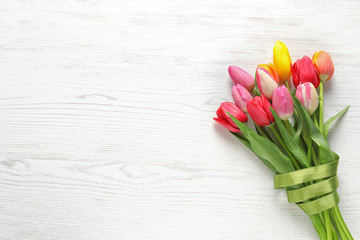 Beautiful bouquet of spring tulip flowers on wooden background, top view. Space for text