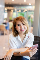 Young beautiful Asian lady celebrate with smart phone in the street in a sunny summer day, success happy pose, internet technology.