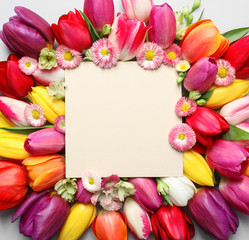 Beautiful composition with spring flowers and blank card on white background, top view. Space for...