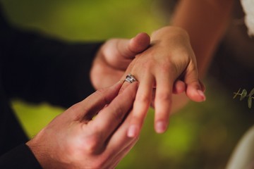 Wedding day. The groom places the ring on the bride's hand. Photo closeup