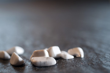 Fototapeta na wymiar Small smooth white pebbles on dark background