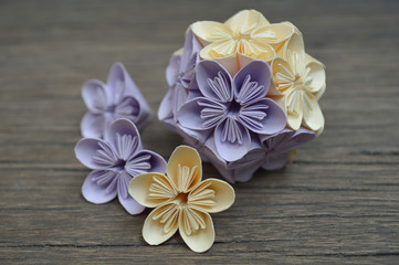 Fototapeta na wymiar Purple and yellow origami kusudama flower on wooden background