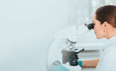 Scientist Looking Through Microscope and concentrate. Scientist examining a human sample on a glass slide at laboratory