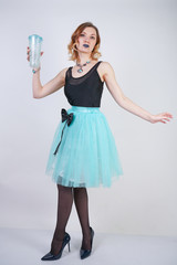 charming blonde teenager girl in a bright dress with a transparent glass of water on a white background in the Studio