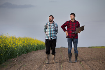 Farmers with laptop in rapessed field