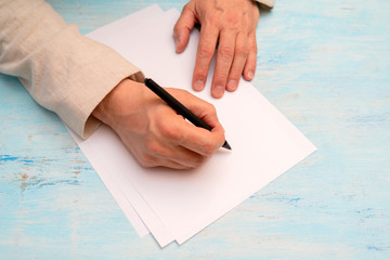 A pen in a man's hand. White sheet of paper. Signing a document.