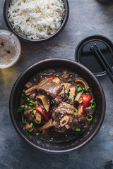 Hainanese lamb stew in a black pot with rice and beer