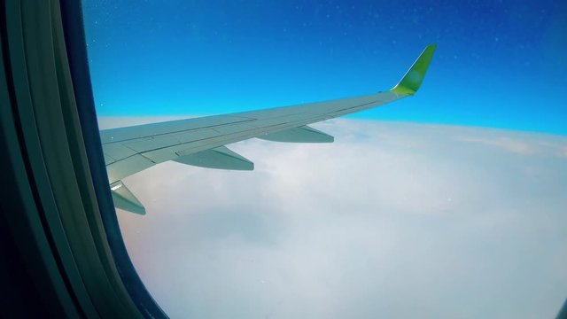 One airplane wing in the sky while a plane flies.