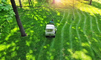 Aerial. Green grass trimming with professional lawn mower machine. Top view.