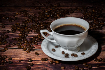 Cup of coffee surrounded by coffee beans  on wooden table.
