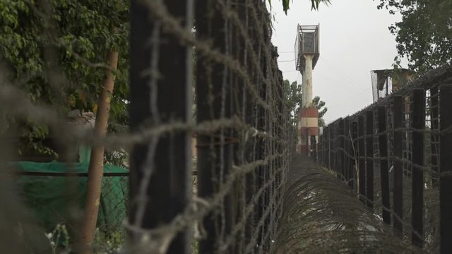View looking along a bard wire barrier towards a guard tower on the border between India and Pakistan