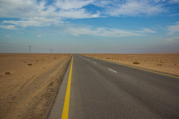 driving transportation object country side empty car road through big desert sand valley outdoor scenery landscape with blue sky with background horizontal line with blue sky and  white clouds 