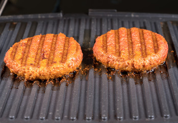 Close shot of the meat like plant-based patties for vegetarian beef burgers being grilled on hot griddle