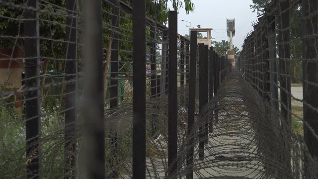 View looking along a bard wire barrier towards a guard tower on the border between India and Pakistan