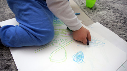 The child learns to draw wax crayons on the floor