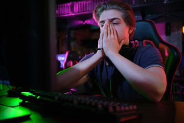 Professional young caucasian gamer playing online on his PC. He upset because of losing the game