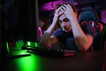 Professional young caucasian gamer playing online on his PC. He upset because of losing the game © nazarovsergey