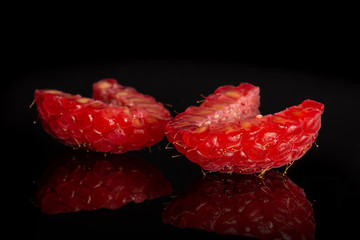 Group of two halves of fresh red raspberry isolated on black glass