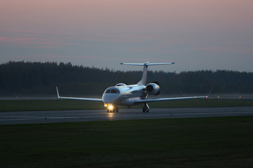 Private jet plane taxiing on the runway in the dark, ready to take off. Business aviation. 