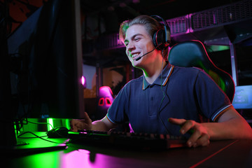Professional young caucasian gamer playing online on his PC. He upset because of losing the game