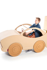 adorable boy playing with cardboard car on white with copy space