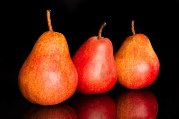 Group of three whole fresh red pear in row isolated on black glass