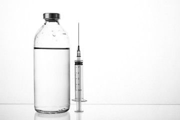 medical drugs and beauty products in glass jars for injections with a syringe with a needle on a white background