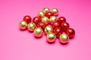 Chocolates in a multi-colored foil on a pink background