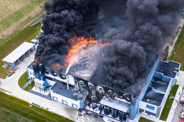 Aerial view of burnt industrial warehouse or logistics center building after big fire with huge smoke from burned roof - 266614289