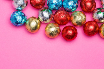 Chocolates in a multi-colored foil on a pink background