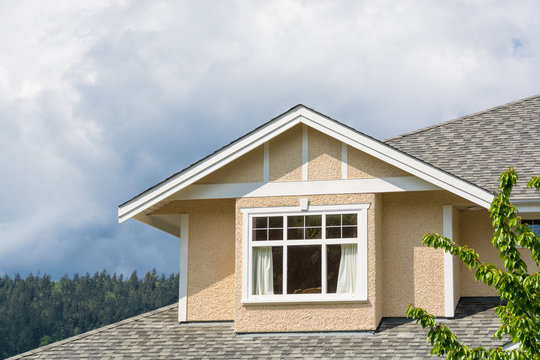 The top of the house with nice windows on cloudy sky background