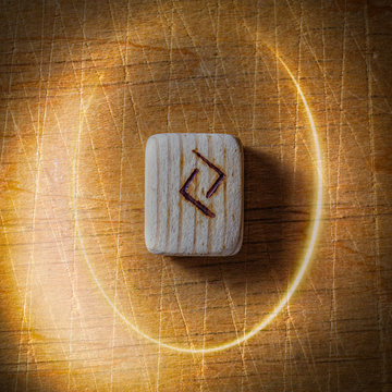 Jera. Handmade scandinavian wooden runes on a wooden vintage background in a circle of light. Concept of fortune telling and prediction of the future.