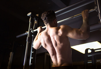 Fototapeta na wymiar Back view of muscular man , young bodybuilder with perfect body doing pull up exercise with gym bar