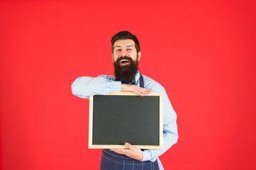 bearded hipster cook in apron. menu board in cafe. welcome. Restaurant or cafe advertising. great cuisine. cooking by recipe. happy man chef in cafe with blank blackboard, copy space. cafe relax