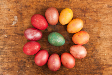 Easter eggs on a wooden background. Happy easter. Bright multicolored shiny easter eggs. Copyspace. Multicolored eggs are lying in circle. Place for text