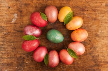 Easter eggs on a wooden background. Happy easter. Bright multicolored shiny easter eggs. Copyspace. Multicolored eggs are lying in circle. Place for text