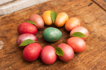 Easter eggs on a wooden background. Happy easter. Bright multicolored shiny easter eggs. Copyspace. Multicolored eggs are lying in circle. Place for text