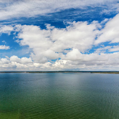 Naklejka na ściany i meble Aerial view of cloudy blue sky over green lake