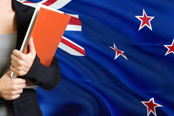 Learning language concept. Young woman standing with the New Zealand flag in the background....