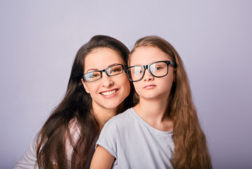 Happy young casual mother and smiling kid in fashion glasses hugging on purple background with empty copy space.