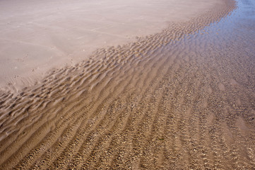 Fototapeta premium Wellen am Strand. Das Wasser trifft auf den weißen Sand.
