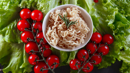 Background of lettuce leaves and a wooden table, a ready-made dish of vegetable noodles and a sea of products are being detained and then tried (eaten) with Chinese sticks. Concept: Shrimps, Vegetable