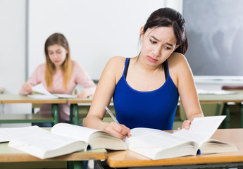 Portrait schoolgirl who is solving a difficult task at the desk