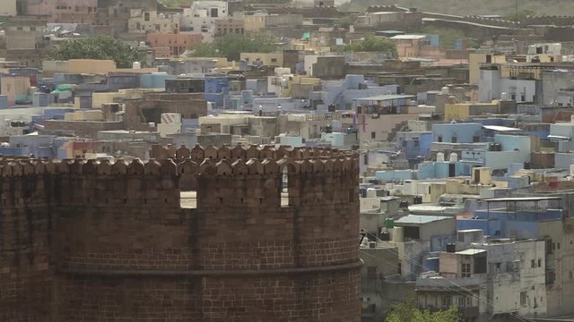 Wide shot of dense houses and buildings in Jodhpur, framed behind ancient battlements of Mahrangarh Fort